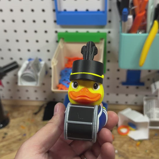 Band Drummer Duck turned in hand to show the plumed hat, striped band uniform and bass drum from every side