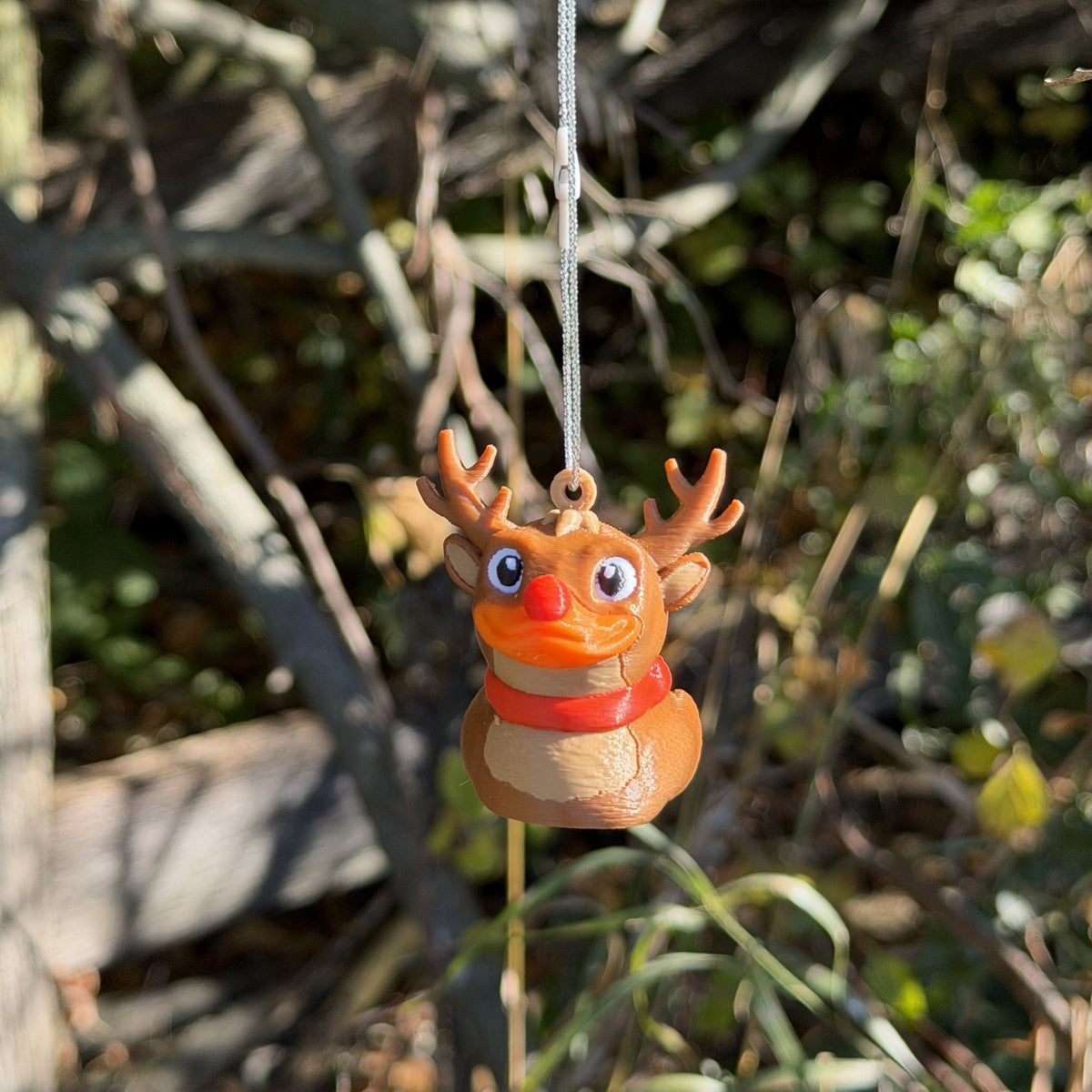 Close view of the reindeer duck ornament hanging from a tree branch outdoors